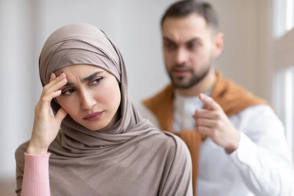 Aggressivo musulmano marito gridando a depresso moglie in piedi a casa — Foto Stock