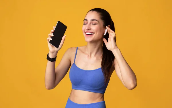 Sorrindo Jovem Mulher em Sportswear Ouvindo Música Segurando Celular — Fotografia de Stock