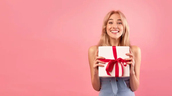 Splendida giovane modella bionda in possesso di scatola regalo su sfondo rosa studio, panorama con spazio libero — Foto Stock