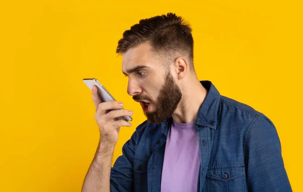 Pria berjanggut marah berteriak di smartphone atas latar belakang studio oranye, panorama — Stok Foto