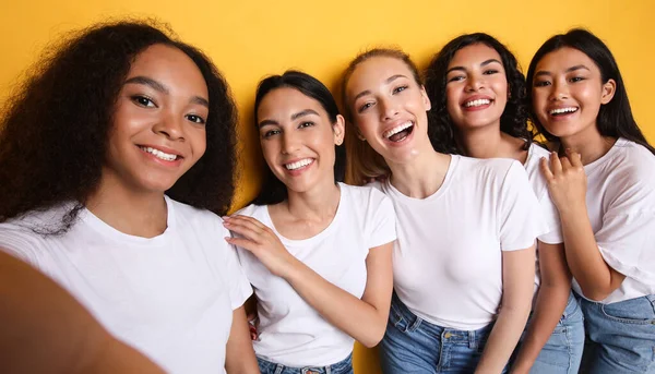 Grupo de cinco mujeres haciendo selfie de pie sobre fondo amarillo —  Fotos de Stock