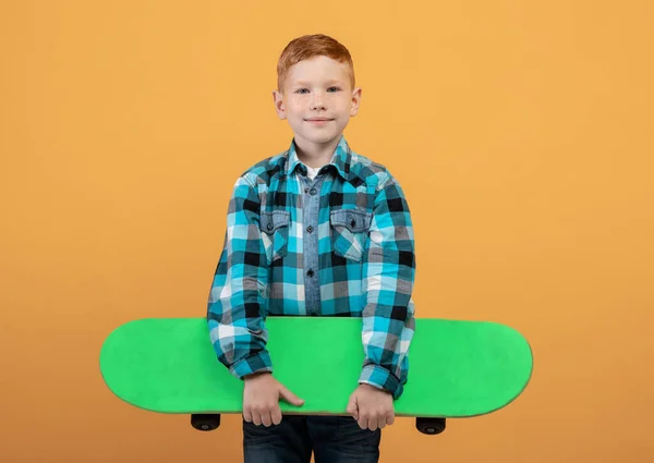 Niño de pelo rojo positivo con cubierta de skate en amarillo — Foto de Stock