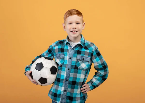 Garçon posant avec ballon de football sur jaune — Photo