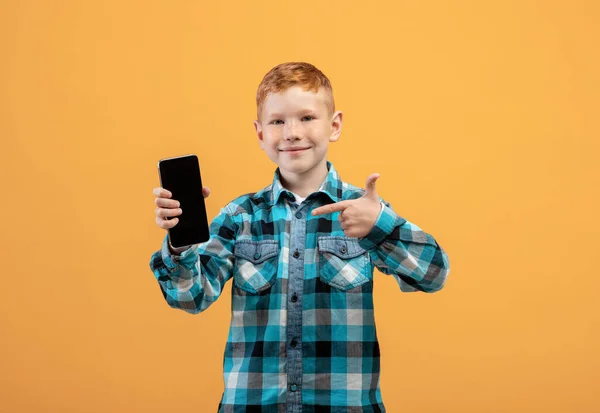 Sonriente niño apuntando al teléfono móvil con la pantalla vacía — Foto de Stock