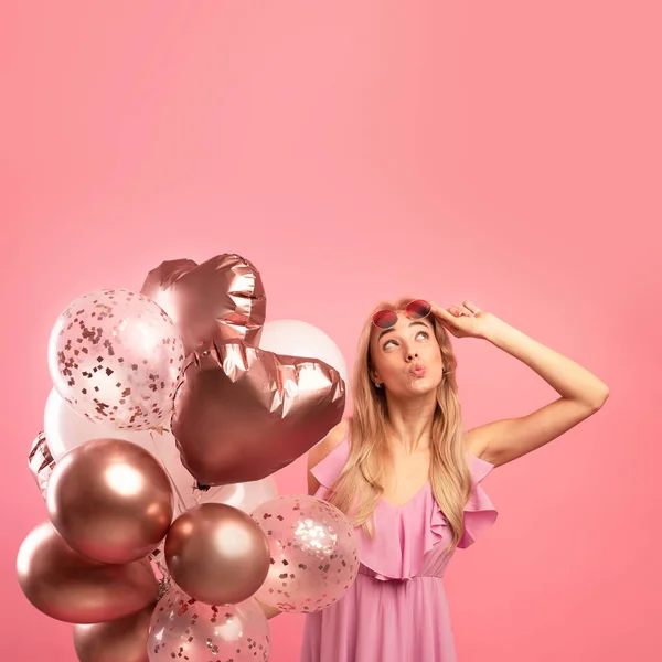 Concepto de venta de vacaciones. Linda mujer rubia sosteniendo un montón de globos, moviendo los labios y mirando hacia arriba en el espacio de copia — Foto de Stock