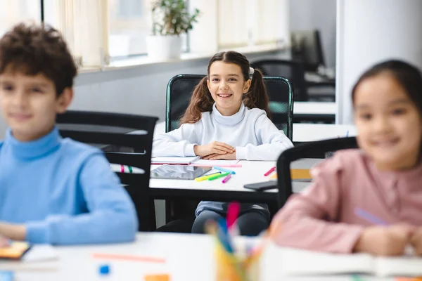 Portrait of small girl sitting at desk in classroom — Stock Photo, Image