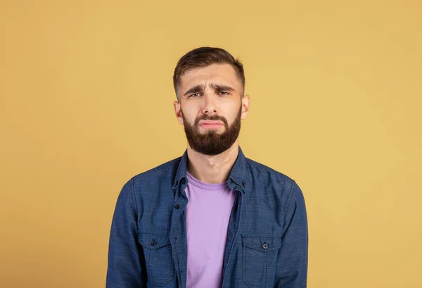 Young Caucasian man feeling unhappy and depressed, crying or whining on color studio background
