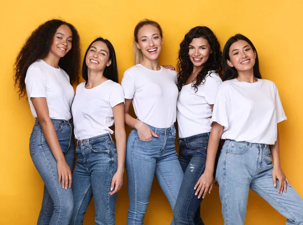 Cinco mulheres felizes de etnia diversa posando juntas, fundo amarelo — Fotografia de Stock