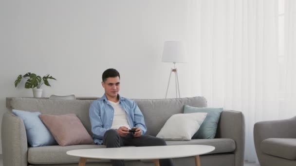 Ung man som spelar tv-spel med joystick, förlorar och känner sig irriterad, slow motion — Stockvideo