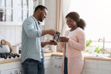 Günaydın Kahve. Genç Afrikalı Amerikalı çift, rahat mutfağında kafein içeceklerinin tadını çıkarıyorlar.