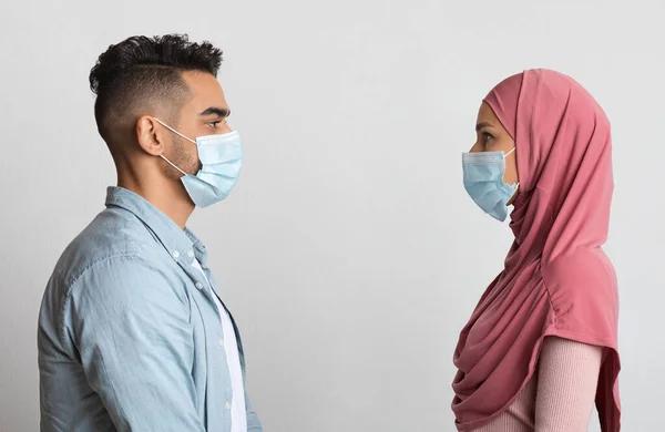 Sociaal Afstandelijk Concept. Profiel schot van moslim paar in beschermende medische maskers — Stockfoto