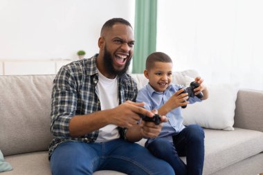 Heyecanlı Afrikalı baba ve oğul evde oturmuş oyun oynuyorlar.