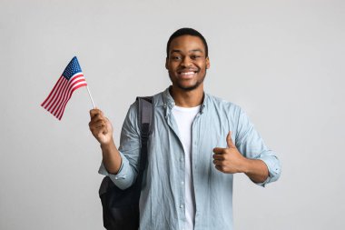 Mutlu siyah adam baş parmağını gösteriyor ve Amerikan bayrağı
