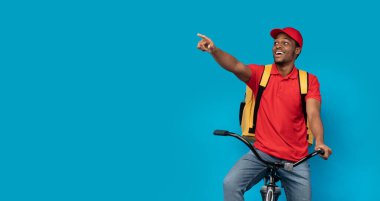 Bisiklete binen siyahi teslimatçı, boşluğu işaret ediyor.