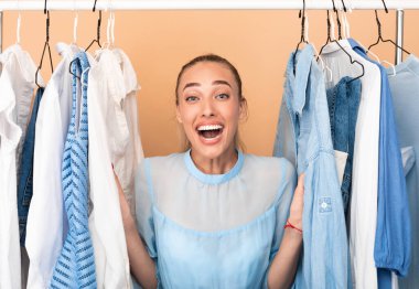 Neşeli kadın sevinçten çığlık çığlığa kıyafet seçiyor.