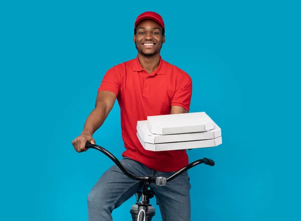 Repartidor negro sosteniendo cajas de pizza, montando bicicleta — Foto de Stock