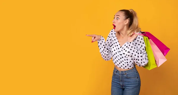 Giovane donna con borse della spesa che puntano a spazio copia — Foto Stock