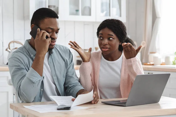 Worry Black Couple Sitting In Kitchen With Financial Papers, Calling To Bank — Stock Photo, Image