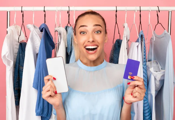 Emocionado mujer elegante celebración de teléfono celular y tarjeta de crédito —  Fotos de Stock