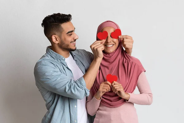 Couple musulman joyeux s'amusant ensemble le jour de la Saint-Valentin, tenant des coeurs rouges — Photo