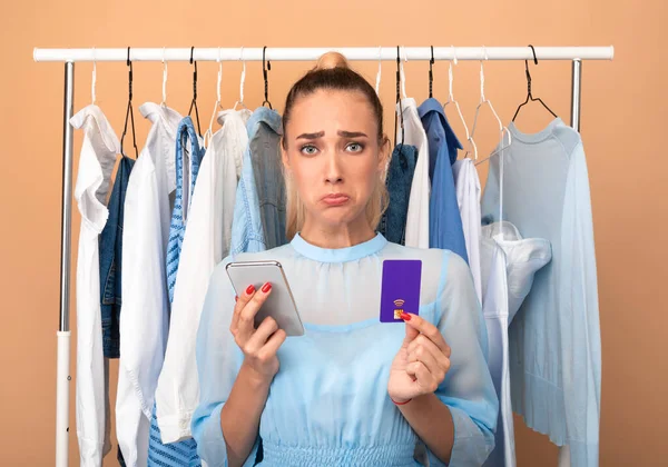 Senhora elegante triste segurando telefone celular e cartão de crédito — Fotografia de Stock