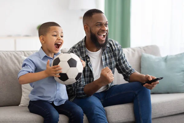 Alegre Africano pai e filho assistindo esportes no interior da TV — Fotografia de Stock