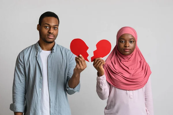 Розчарований чорний чоловік і жінка тримають половинки розбитого серця — стокове фото