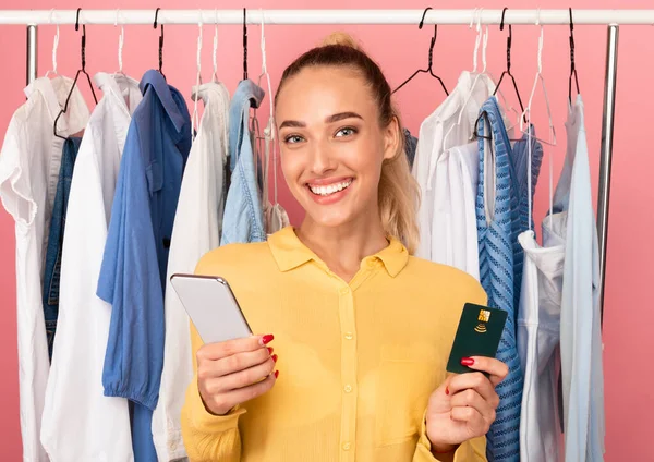 Sonriendo elegante dama sosteniendo el teléfono celular y la tarjeta de crédito —  Fotos de Stock