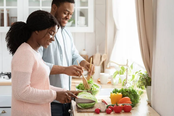 Atractiva pareja afroamericana preparando comida para el almuerzo juntos, cocinando en la cocina — Foto de Stock