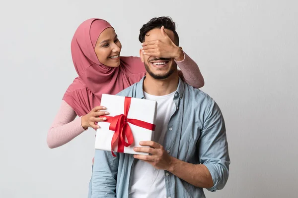 히잡에 나오는 사랑 스러운 여장 여자는 선물 상자를 가지고 있는 남편을 놀라게 한다 — 스톡 사진