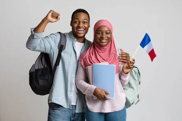 Feliz preto muçulmano estudantes casal segurando francês bandeira — Fotografia de Stock