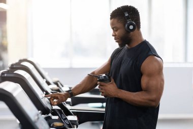 Koşu bandında protein içeceği olan kaslı zenci adam.