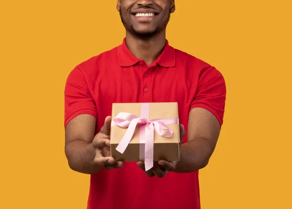 Zwart guy holding gift box tonen naar camera — Stockfoto