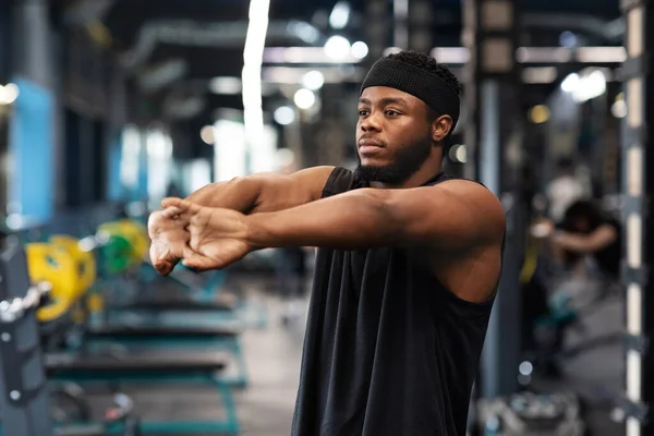 Athletisch schwarz kerl stretching hände im fitnessstudio — Stockfoto