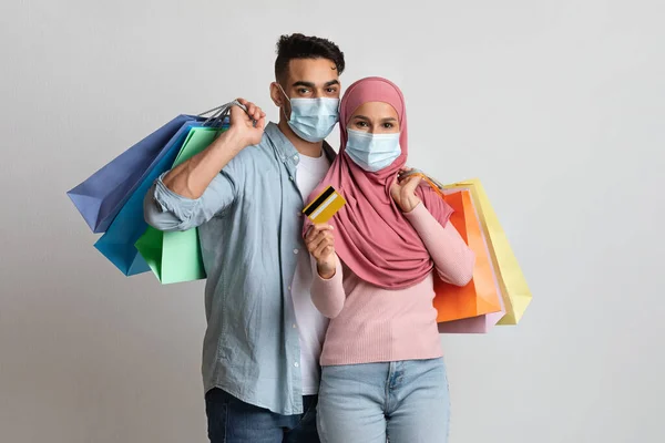 신용카드와 종이 쇼핑백을 들고 마스크를 쓴 행복 한 부부 — 스톡 사진