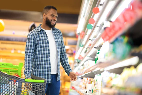 Afro-americano cara compra comida de pé perto prateleira no supermercado — Fotografia de Stock