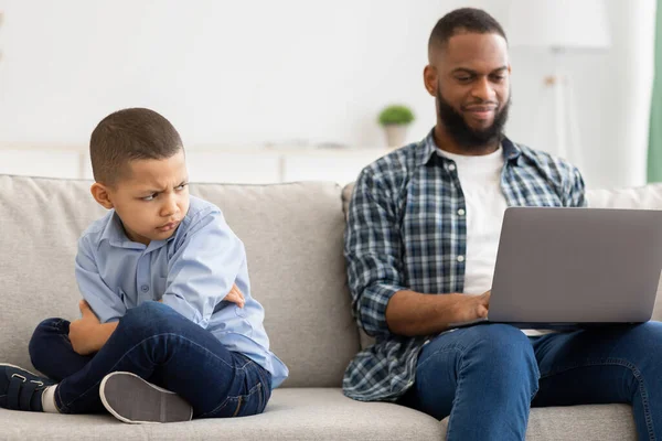 Αδιαφοροποίητος μαύρος πατέρας παραμελεί το γιο χρησιμοποιώντας το lap-top που κάθεται στο σπίτι — Φωτογραφία Αρχείου