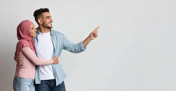 Kijk daar. Jonge moslimechtgenoten wijzen naast op grijze Studio achtergrond — Stockfoto