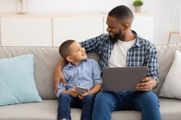 African Daddy And Little Son Using Digital Tablet At Home