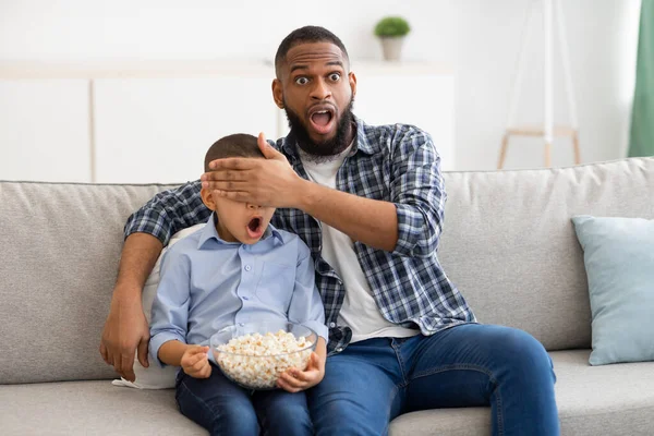 Schockierter schwarzer Vater deckt Söhne beim Fernsehen zu Hause — Stockfoto