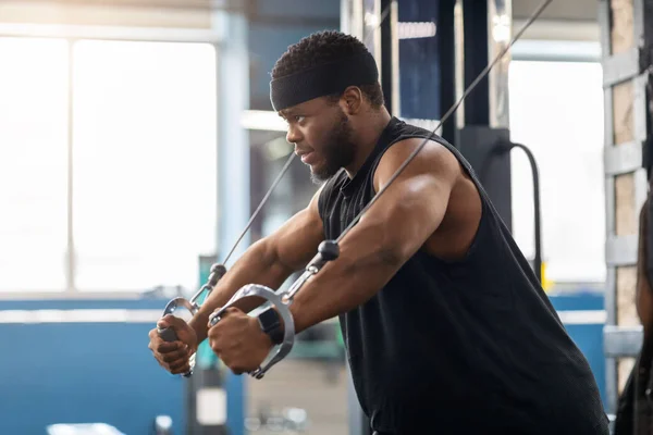 Young black sportsman training triceps on block exerciser in gym — Stock Photo, Image