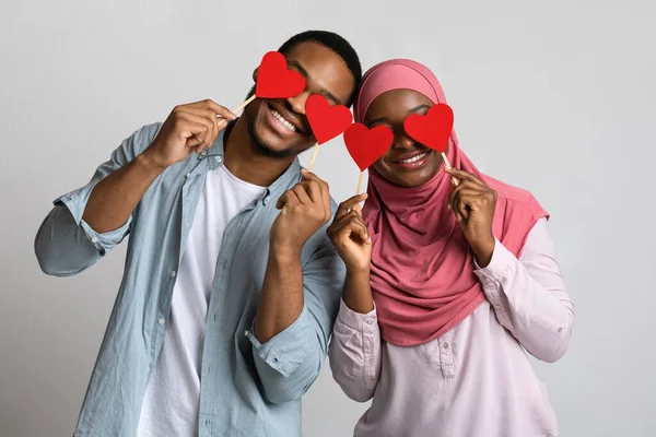 Молода чорношкіра мусульманська пара тримає червоне серце любові над очима — стокове фото