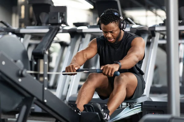 Motivierter schwarzer Sportler beim Training auf dem Rudergerät — Stockfoto