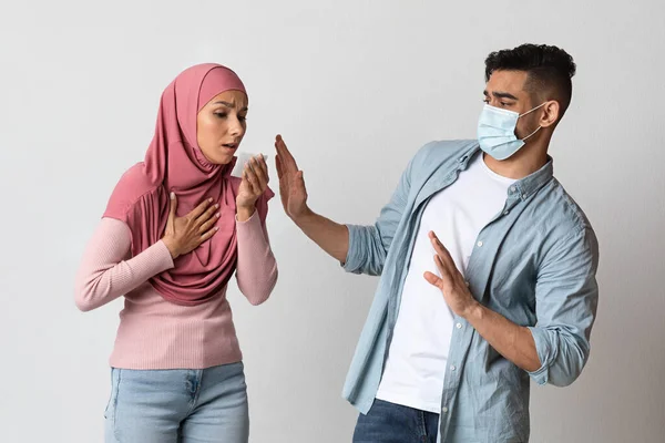 코로나 포비아. 의료용 마스크를 쓴 걱정 스러운아 라브 남자는 기침하는 사타구니 여자를 두려워하고 있다 — 스톡 사진