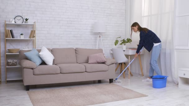 家でモップとバケツを使って床を掃く若い女性スローモーション — ストック動画