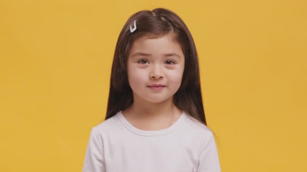 Studio πορτρέτο του χαριτωμένο κοριτσάκι χαμογελώντας στην κάμερα, πορτοκαλί φόντο — Αρχείο Βίντεο