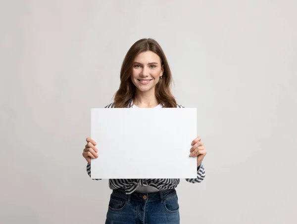 Schöne junge Frau hält leeres Plakat mit Kopierplatz für Werbung — Stockfoto