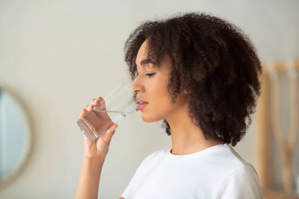 Mujer sedienta sostiene las bebidas de vidrio agua quieta prevenir la deshidratación —  Fotos de Stock