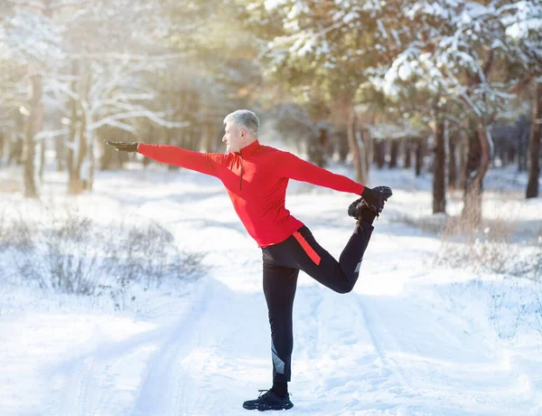 Full length of mature man in sportswear warming up before running outdoors on snowy winter day. Healthy lifestyle — Stock Photo, Image