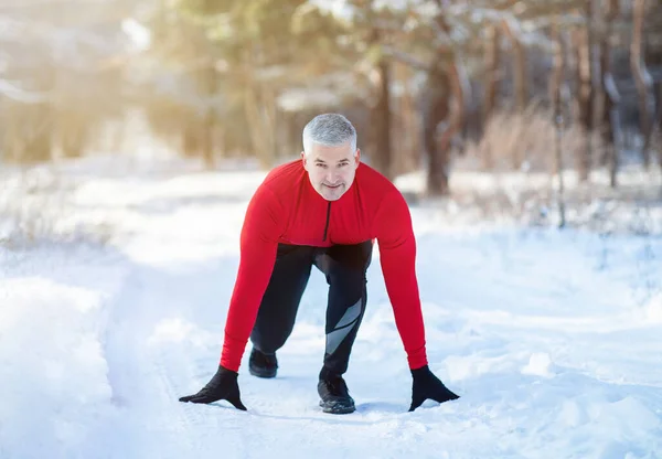 Hombre mayor listo para correr por el camino del campo con nieve en el frío día de invierno. Estilo de vida activo y concepto de aclimatación —  Fotos de Stock